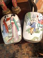 Front view of two rectangular porcelain-lid trinket boxes showing enamel decoration of figural scenes