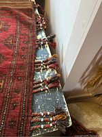 Close-up showing red and brown tassels attached to the edge of one Kilim saddle bag.