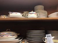 Wide view of shelves showing plates, cups, lidded casserole and serving pieces in Edelstein Bavarian china pattern