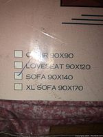 Close-up of packaged linen size label checked at sofa 90x140 cm, showing size options.