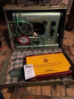 Full view of the sewing machine in metal case with power cords and the Burgess Vibra-Tool leather craft kit box in front