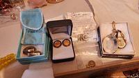 Overview photo showing multiple jewelry items including cufflinks and necklace pendants on table.