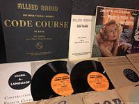 Close-up photo showing Allied Radio International Morse Code Course box and booklet with two French conversation records and a Jackie Gleason record cover.