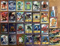 Top view of 28 Digimon trading cards arranged in 4 rows with various characters including Garudamon, Phantomon, MegaSeadramon, Tentomon, Gomamon, and others.