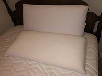 Two large rectangular off-white memory foam body pillows shown on bed, clean and in good condition.