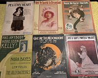 Flat lay photo showing six larger vintage sheet music covers with various titles and vintage photos