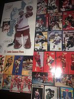 Photo showing assortment of hockey cards including Tall Boy Parkhurst, Kraft Dinner promo cards, 3 Post cereal cards, and a large Red Wings poster.