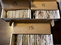 Three open cardboard boxes filled with hockey trading cards seen from above, each marked with number 15 on box lid.