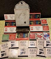Photo of the vintage metal wall-mounted matchstick holder surrounded by various matchbooks and matchboxes including brands like Point Ideal Resort Marina, Chrysler Electronic Ignition, Dewey Smith & Sons Limited, and Eddy Quality Matches.
