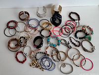 Overview photo of bracelets spread on a flat surface showing variety of materials, colors, and styles.