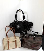 Full view of three handbags: black Juicy Couture handbag, beige Liz Claiborne satchel, and multicolor Calvin Klein tote.
