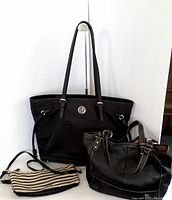 Three handbags displayed side by side against white background: Kate Spade black tote, The Sak black leather bag, and small striped crossbody bag.