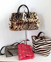Four handbags displayed including zebra faux fur handbag, striped crossbody, zebra print tote, and framed bag with scarf.