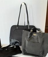 Three bags shown on display stand: The Sak crochet handbag with leather accents, BCBG black tote with logo plaque, and black laptop tote with pink interior.