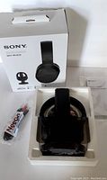 Sony WH-RF400 headphones placed in white plastic tray with charging cable and user manual next to original white box.