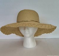 Front view of beige floppy sun hat with wide brim and crochet edging on mannequin head.