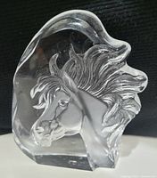 Photo of a clear glass sculpture of a horse's head with detailed etched mane and features, showing condition and design.