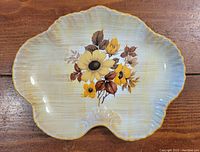 Shell-shaped serving dish with floral design on wood surface.