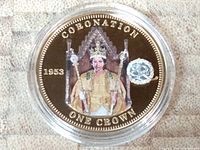 Reverse side of coin featuring seated Queen Elizabeth in regalia, gold plating and platinum privy mark with text 'CORONATION ONE CROWN 1953'.