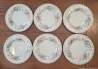 Top view of six lunch plates showing Jubilee Rose floral pattern along the rims with scalloped edges and embossed detailing.