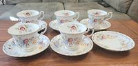 Front view of 5 Royal Albert Jubilee Rose teacups and 6 saucers arranged on a wooden surface.
