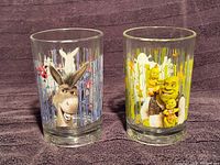 Two Shrek-themed drinking glasses side by side, one with Donkey, one with Shrek and babies