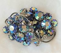 Top view of the small brooch showing blue and iridescent rhinestones with silver butterfly decorations.