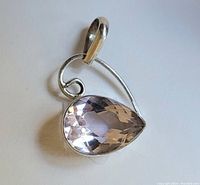 Close-up photo of a sterling silver pendant with a pear-shaped pale pink faceted stone, showing the design and setting details.