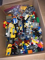 Top-down view of open box filled with colorful assorted LEGO bricks and elements showing variety of shapes and colors.
