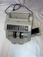 Front view of electronic bill counter showing keypad, digital display, and power cord.