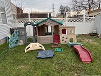 Full view of assembled outdoor play house with additional pieces on grass