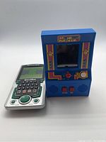 Two handheld games shown side by side; Ms. Pac-Man mini arcade game on right, Scholastic Bridge handheld game on left