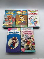 Front view of 5 cartoon VHS tapes showing colorful cartoon artwork on the cases including Rocky and Bullwinkle, Top Cat, Bozo, Herman the Mouse, and Courtin' Cut-Ups