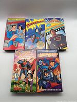 Front view of 5 Superman and Batman VHS tapes with colorful illustrated covers