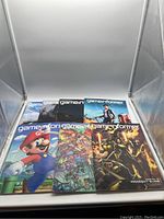 Photo showing all seven Game Informer magazines arranged inside a display box, including visible titles and covers.