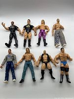 Photo showing 8 wrestling action figures arranged in two rows on a white background; various poses and attire visible