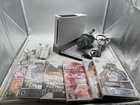 Full bundle with Nintendo Wii console, controller, power adapter, sensor bar and 6 game cases arranged flat.