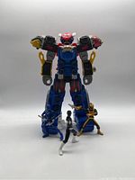 Power Rangers figures and large Zord front view against white backdrop.