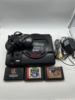 Overall lot showing Sega Genesis Model 1 console with controller, power adapter, AV cable, and three game cartridges placed in front.