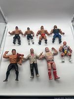Nine vintage wrestling action figures arranged in two rows on white background. Figures show heavy wear and various paint damage.