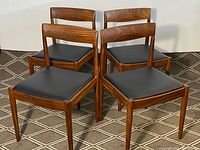Four teak chairs arranged together on patterned carpet