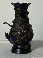 Full view of antique bronze vase showing overall shape, ruffled rim, relief decoration