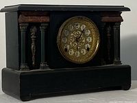 Front view of black wooden case with fluted columns and brass bezel