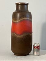 Front view of tall cylindrical vase with brown reactive glaze and red band, shown with a Diet Coke can for scale.