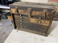 Front of wooden toolbox showing five drawers, metal knobs and latch.