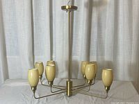 Full view of chandelier showing eight yellow glass shades and brass finish frame