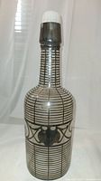 Front view of antique liquor bottle showing silver overlay with geometric lines and decorative central band on glass bottle.