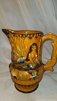 Front angle showing mermaid figure and handle detail on antique Majolica jug.