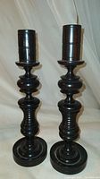 Full view of the pair of black walnut turned wood candlesticks showing their shape, size, and finish.