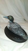 Full view of the hand carved and painted loon bird decoy on the wooden base showing naturalistic paint and glass eyes.